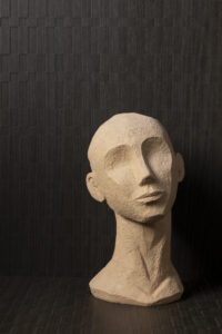 Sfeerafbeelding van de grafische S182 Sbalzo in decoratief plaatmateriaal. Met een stenen hoofd ter decoratie