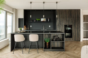 Keukenkasten in decor S171 Bruciato van Cleaf, welke doet denken aan verbrand hout, gecombineerd met een nis in de vingerafdrukbestendige zwarte HM07 Piombo