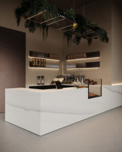 Zijaanzicht van een horecagelegenheid met een bar uitgewerkt in het solid surface decor DM5048 Starstruck van Durasein, welke de luxe uitstraling van marmer op een warm witte basis biedt. De wandafwerking uitgewerkt in de FD29 Taranta van Cleaf, welke de beleving van zandsteen geeft, en een deur in de FD14 Taranta van Cleaf, een bruine steentextuur.