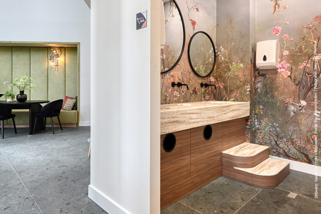 Inspiratiebeeld van een toiletmeubel met meerdere solid surface waskommen Amsterdam in decor DM5002 Weathered Wood naadloos verlijmd. Daarnaast zie je een deel van het horecagelegenheid.
