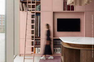 Stijlvolle showroomopstelling met vakkenkast in poederroze UB52 Ovatta, gecombineerd met een walnoot werktafel in LS40 Poro Noce en een Durasein werkblad met marmerlook.