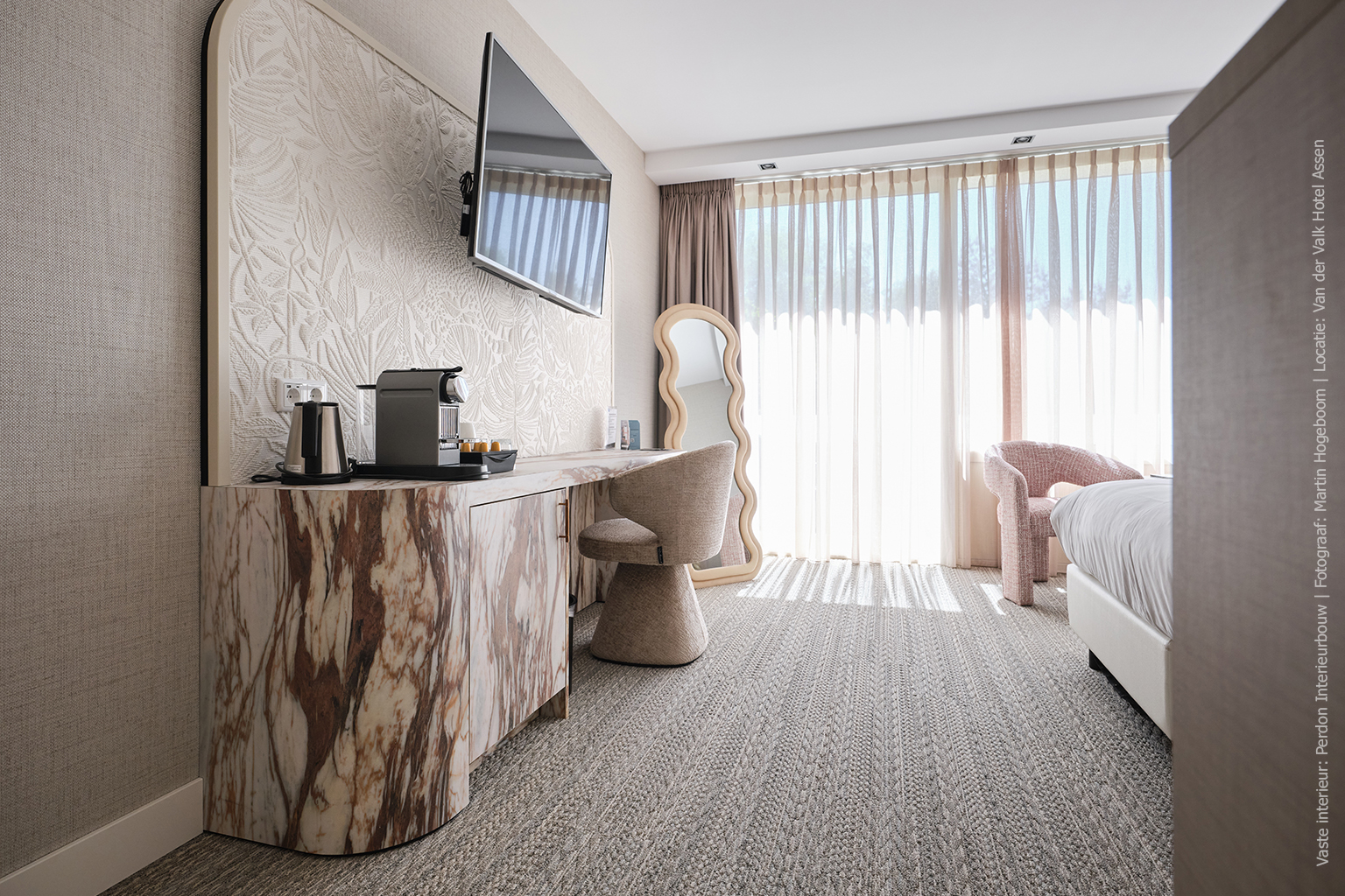 Hotelkamer met een afgerond bureau in marmerdecor D045 Fiocco, met warme bruin-witte aders en zachte tinten.