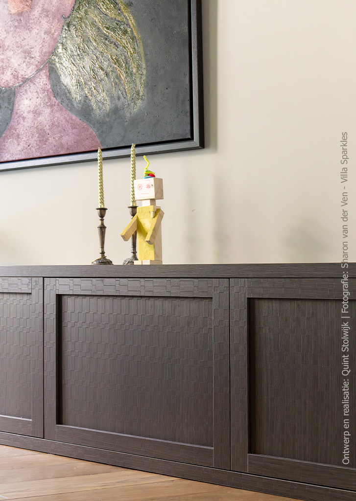 Detailfoto van laag dressoir, uitgevoerd in donkerbruin S181 Sbalzo van Cleaf met geometrische houtstructuur.