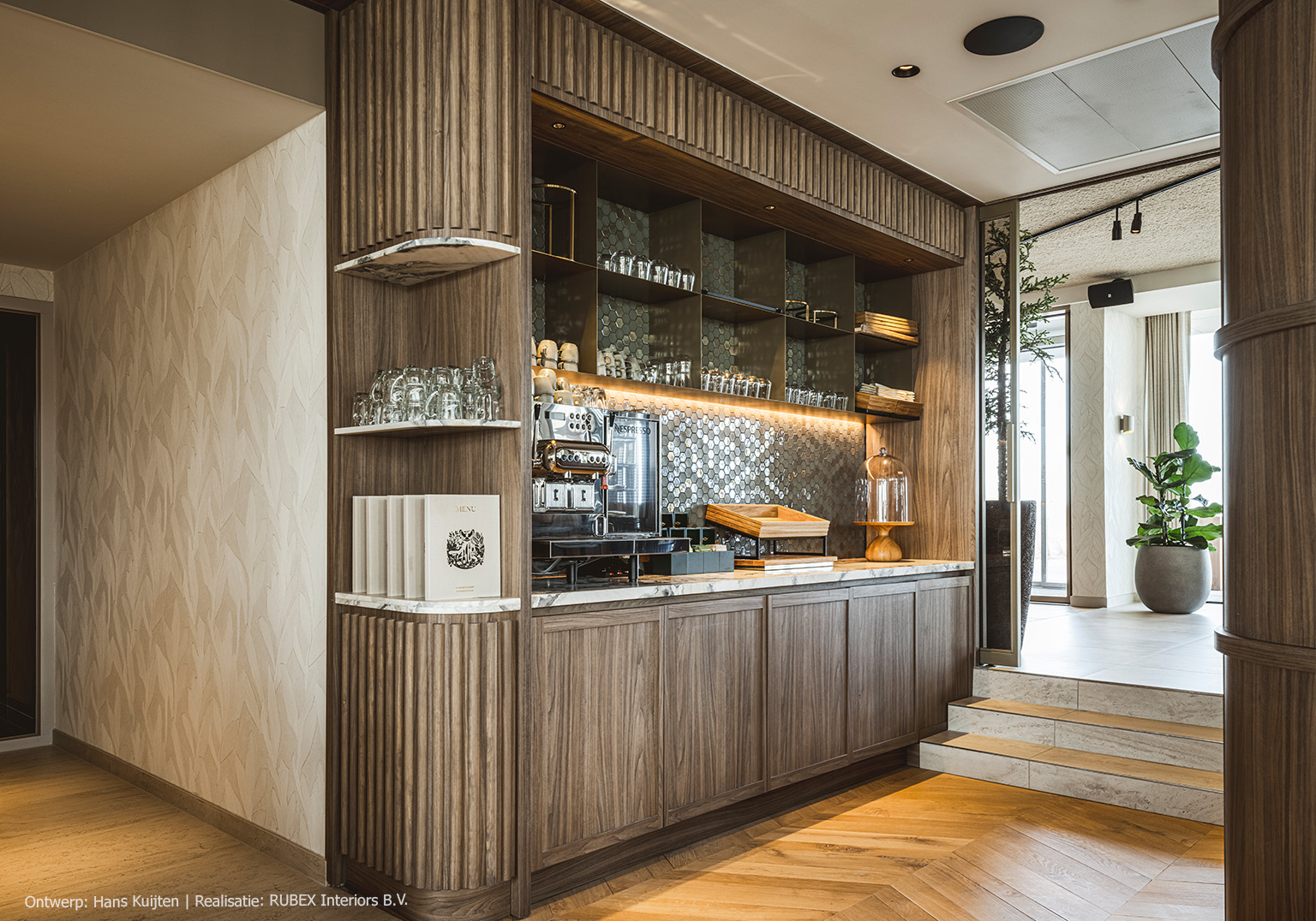 Maatwerk pantry in hotel, uitgevoerd in LS13 Poro Noce, een warm lichtbruin walnootdecor met levendige nerftekening.