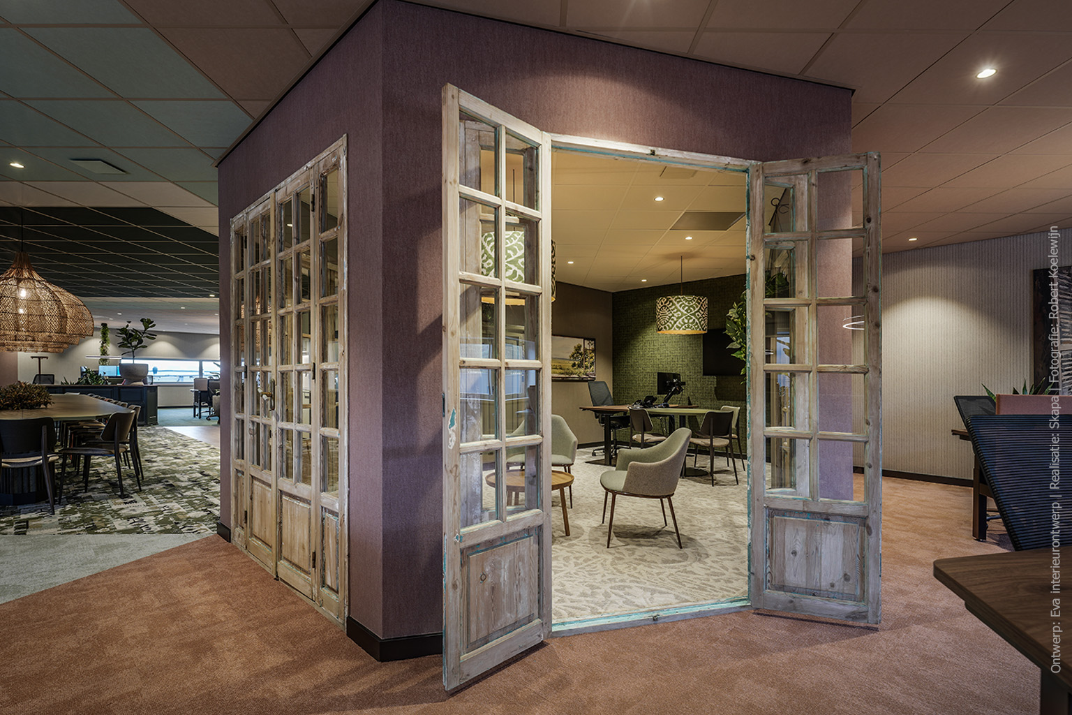 Openstaande houten deuren naar een werk- en overlegruimte met een tafel in legergroene UB54 Primofiore